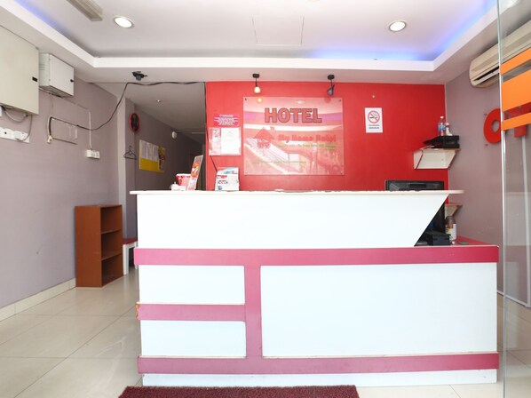 A hotel reception desk with a red and white color scheme, a sign indicating the hotel name, and a no-smoking sign. - OYO 89654 My New Home Hotel (Gua Musang)