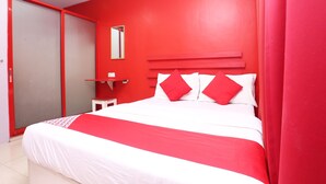 Une pièce avec un lit, un mur rouge, un couvre-lit blanc et un rideau rouge.