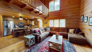 A cozy cabin interior with a wooden interior, a dining area, and a living room with a large sectional sofa. - Acorn Acres is a true log cabin nestled in complete privacy and seclusion on acr (Broken Bow)
