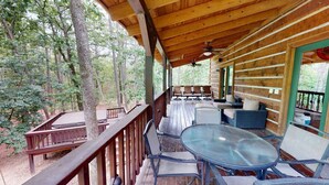 A covered outdoor seating area with wooden tables and chairs, surrounded by trees. - Acorn Acres is a true log cabin nestled in complete privacy and seclusion on acr (Broken Bow)