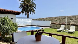 A poolside area with a table, chairs, and a potted plant. - Charming La Jara House with Private Pool and Stunning Mountain Views i (Arico)