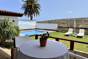 Ein Poolbereich mit Tisch, Stühlen und einem Topfpflanzen.