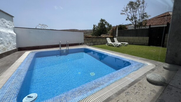 A rectangular swimming pool with a tiled edge, a ladder, and a lounge area with chairs. - Charming La Jara House with Private Pool and Stunning Mountain Views i (Arico)