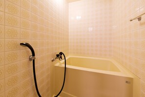 A bathroom with a bathtub, a shower hose, and patterned tiles. - Yumoto Sakakibarakan (Tsu)