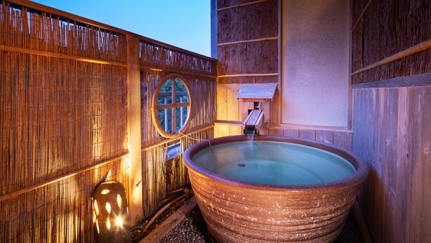 Un espace de détente en bois comprenant un grand bain à remous, une clôture en bois et une petite fenêtre.