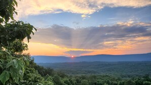 Un coucher de soleil sur un paysage boisé, avec un ciel dégagé.