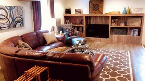 Un salon chaleureux avec un canapé en cuir marron, une petite table basse en bois et un tapis à motifs.
