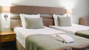 A hotel room with two beds, a nightstand, and a lamp. - Spa Hotel Orbita (Blagoevgrad)