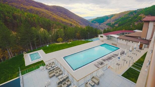A swimming pool with lounge chairs and a view of a mountainous landscape. - Spa Hotel Orbita (Blagoevgrad)