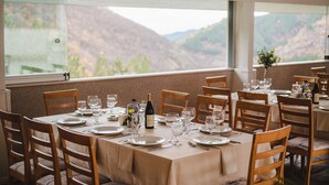 A dining area with tables set for a meal, featuring a view of mountains through large windows. - Spa Hotel Orbita (Blagoevgrad)