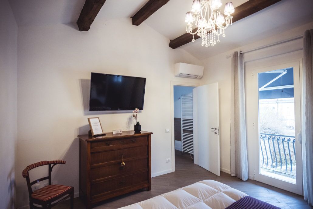 A bedroom with a bed, a dresser, a television, and a chandelier.