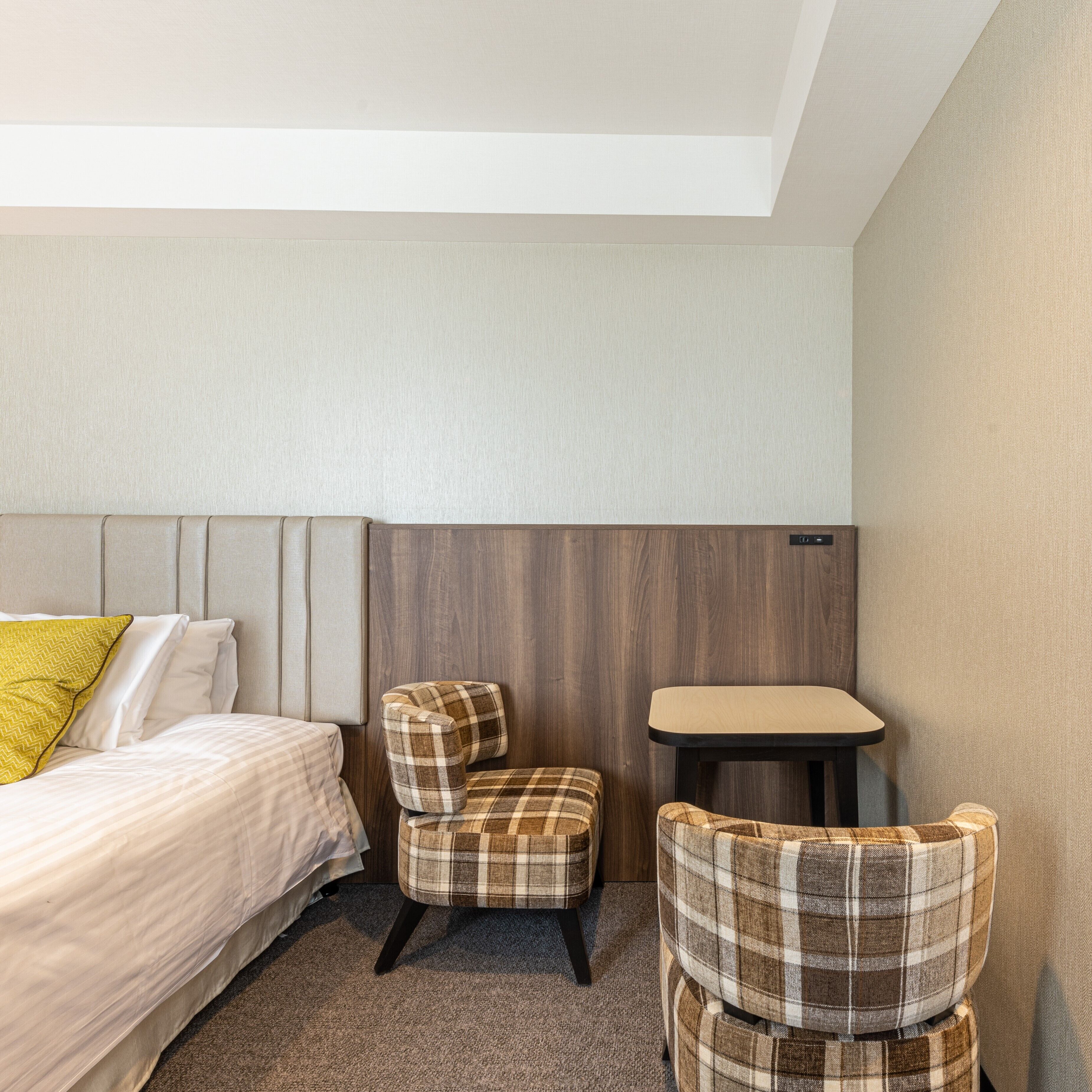 A hotel room with a bed, a small table, and two chairs.