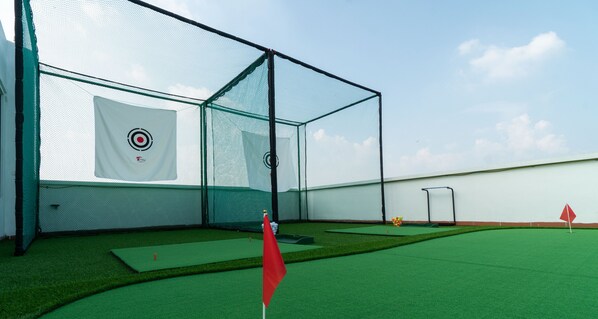 A batting cage with artificial turf, a target, and a netted enclosure.