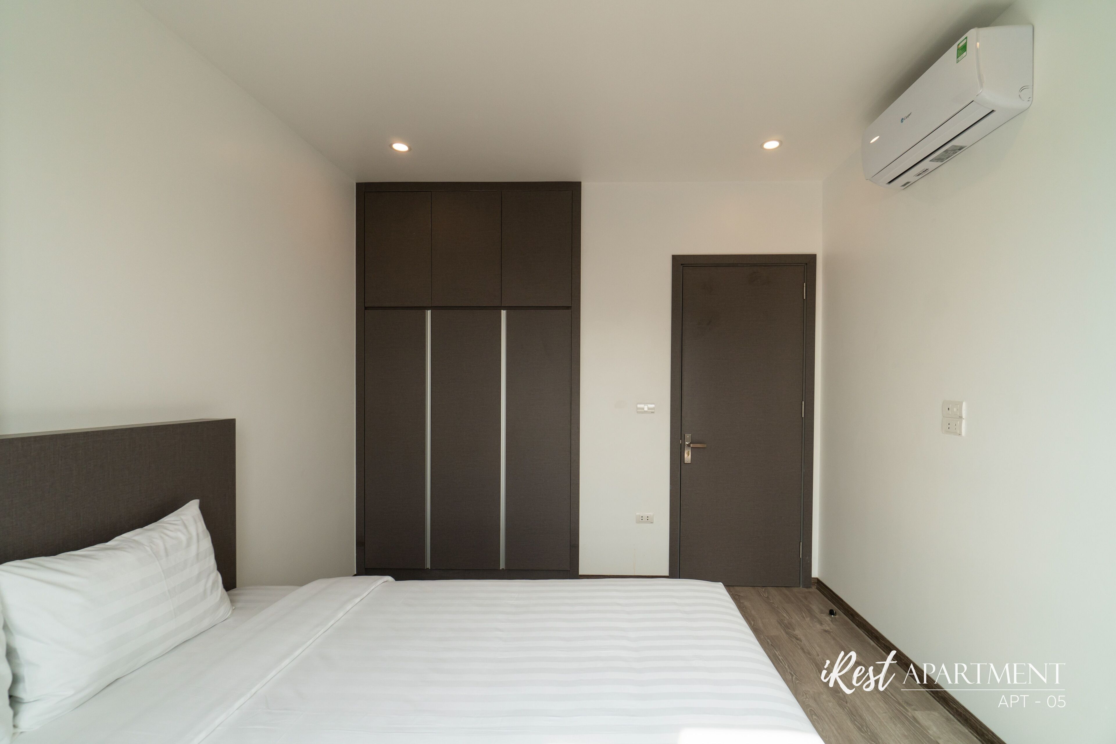 A bedroom with a bed, a wardrobe, and an air conditioning unit.