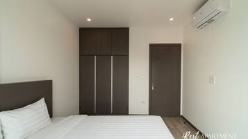 A bedroom with a bed, a wardrobe, and an air conditioning unit.