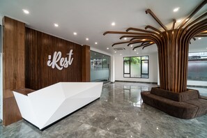 Un área de recepción con un mostrador blanco, paneles de madera y un diseño moderno en el techo.