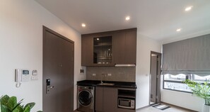 Una cocina funcional con lavadora, microondas y horno empotrado.