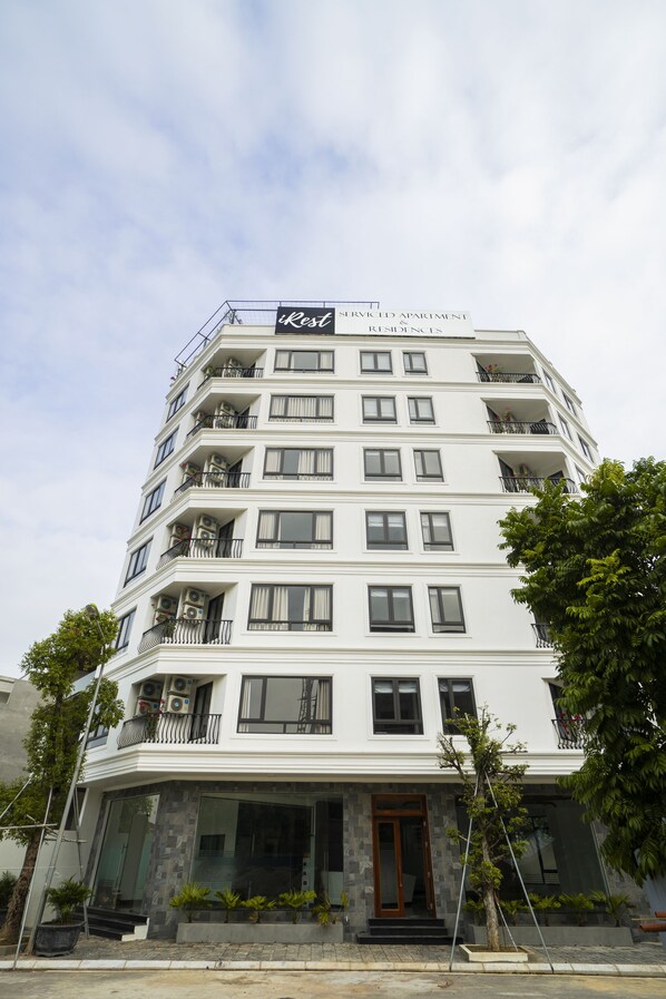 Edificio de apartamentos con servicios, de varios pisos y balcones, con un cartel que indica que se trata de apartamentos con servicios, y cielo despejado al fondo.