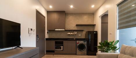A modern kitchen with built-in appliances, a flat-screen TV, and a seating area with a plant.