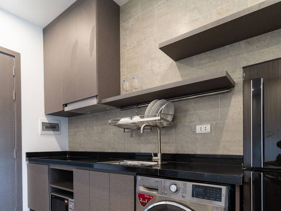 A modern kitchen with built-in appliances, including a washing machine, oven, and microwave.