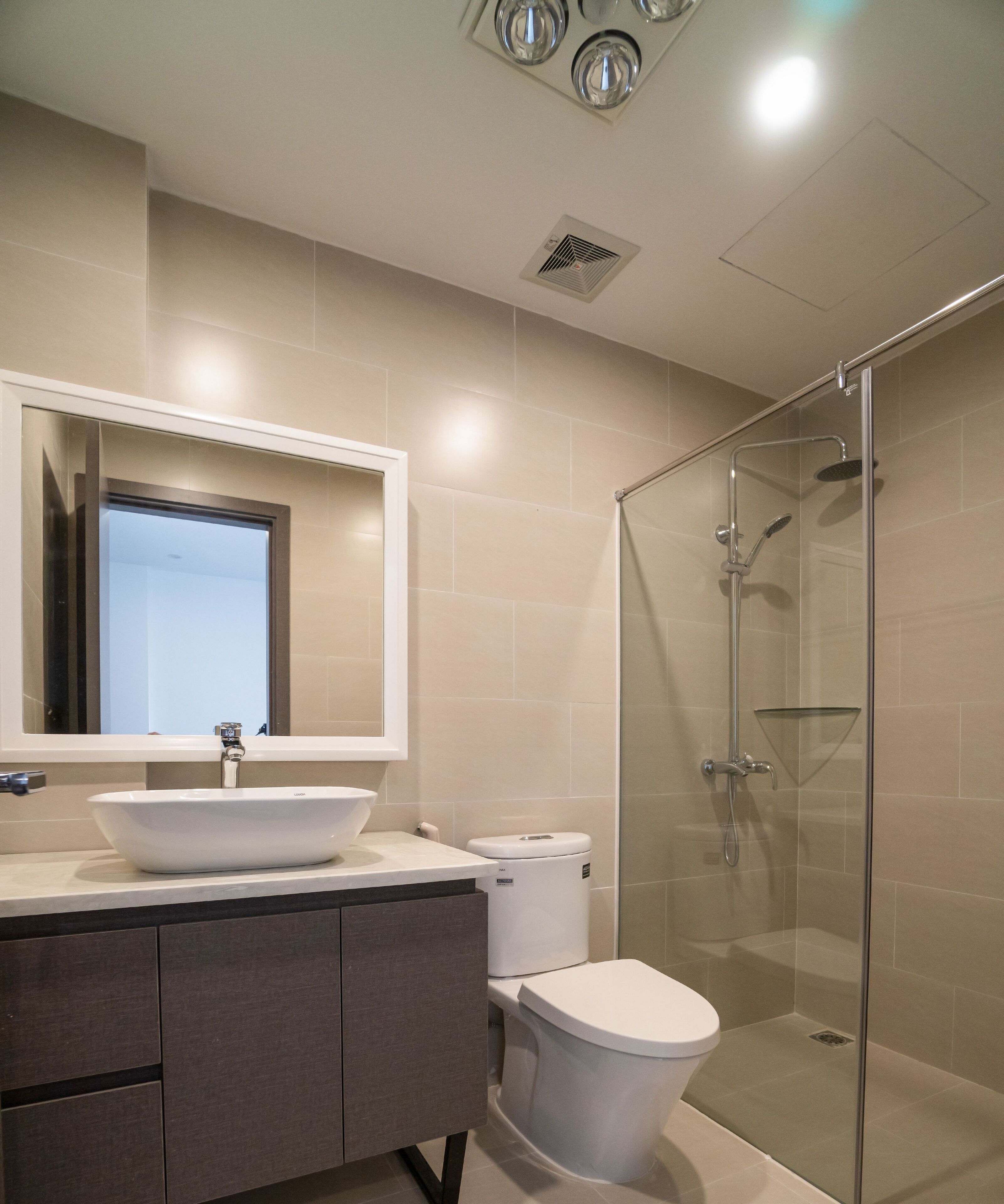 A modern bathroom with a large mirror, a vessel sink, a toilet, and a glass-enclosed shower.