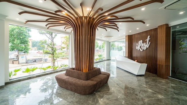 Un espace d’accueil moderne avec une colonne en bois, un canapé marron et un comptoir d’accueil blanc.