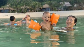 A beach scene with people swimming and holding orange flotation devices. - Mali Koh Kradan (Ko Kradan)