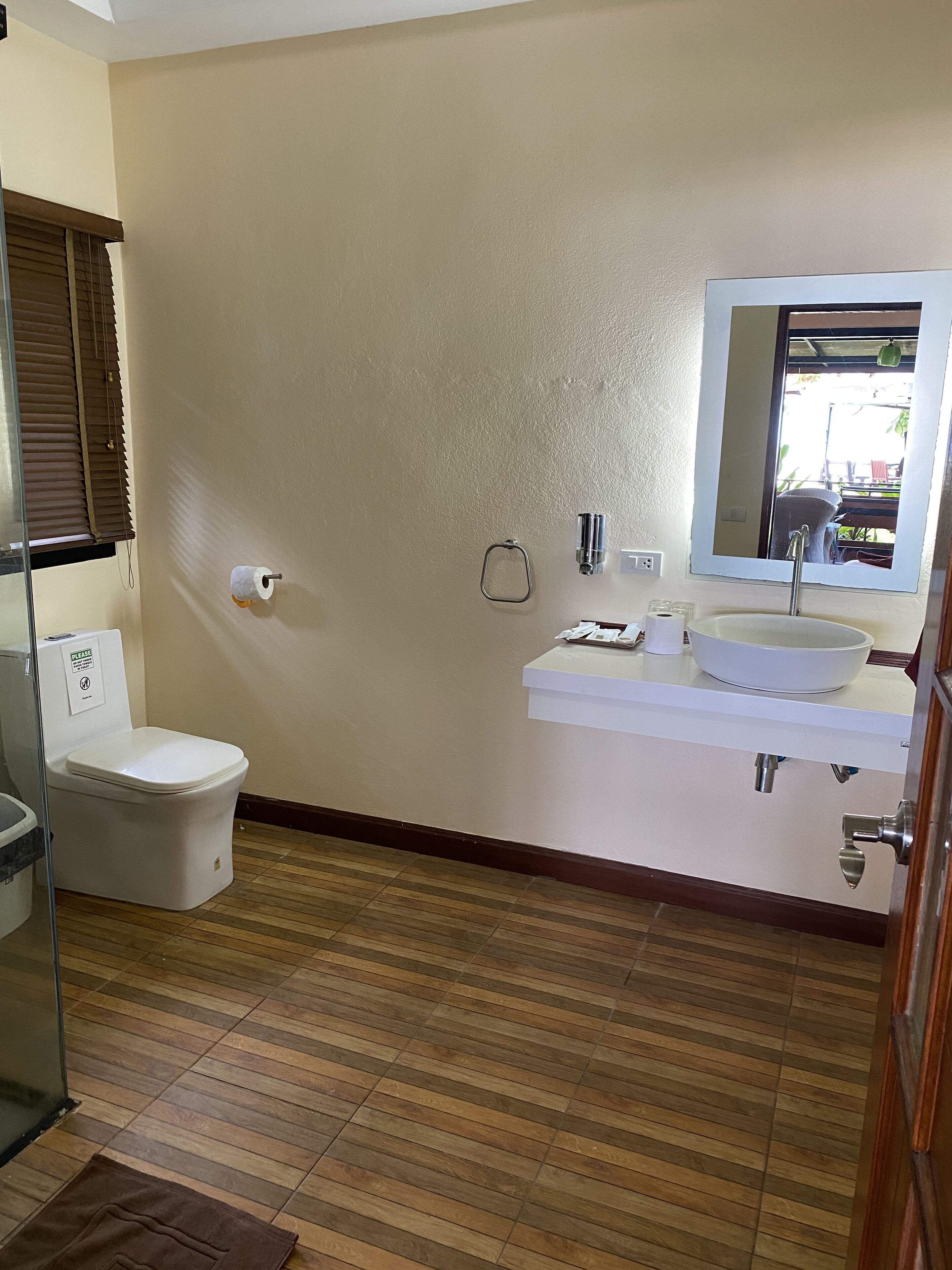 A bathroom with a toilet, sink, and mirror.