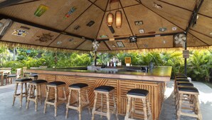A tiki bar with wooden stools and a bar counter, surrounded by lush greenery. - Mali Koh Kradan (Ko Kradan)