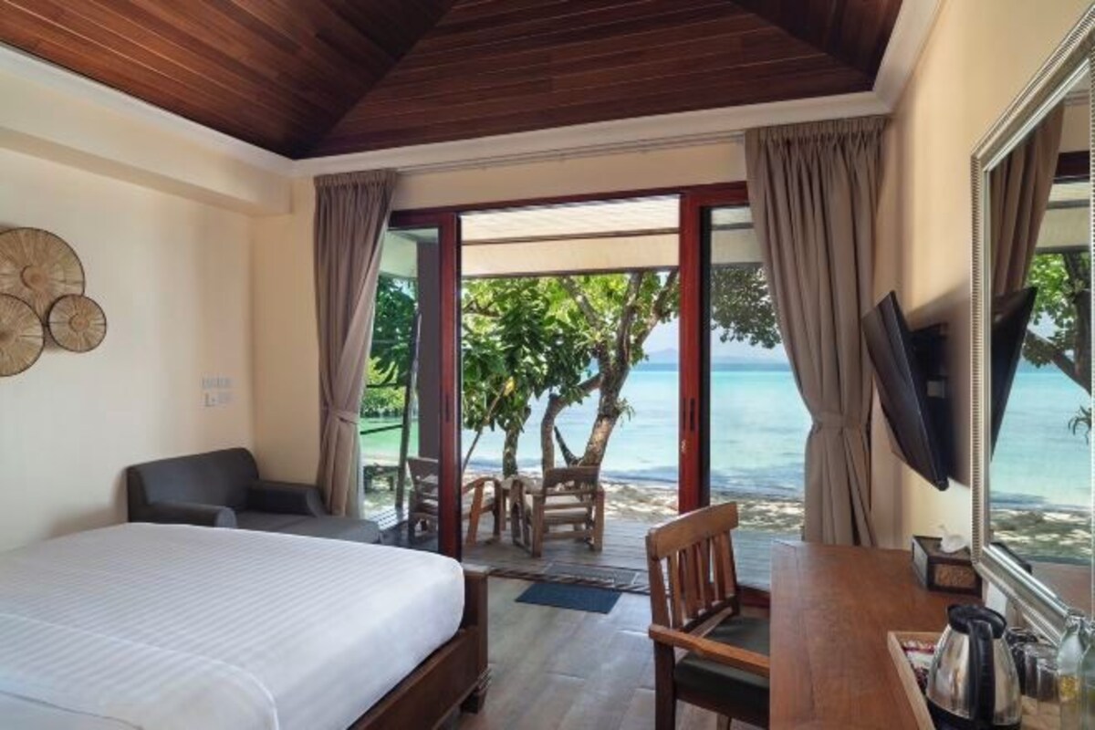 A hotel room with a bed, a desk, and a view of the ocean.