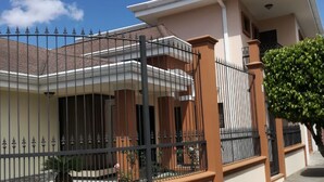 A two-story house with a balcony, a gated entrance, and a small garden area. - Beautiful House, Master Bedroom With A Jacuzzi, Private Balcony, Mountain View! (El Tejar del Guarco)