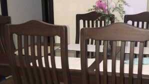 A dining area with four wooden chairs and a table, a vase with flowers, and a door in the background. - Beautiful House, Master Bedroom With A Jacuzzi, Private Balcony, Mountain View! (El Tejar del Guarco)