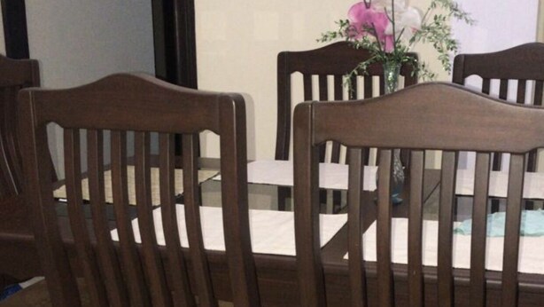 Un coin repas avec quatre chaises en bois et une table, un vase avec des fleurs et une porte en arrière-plan.