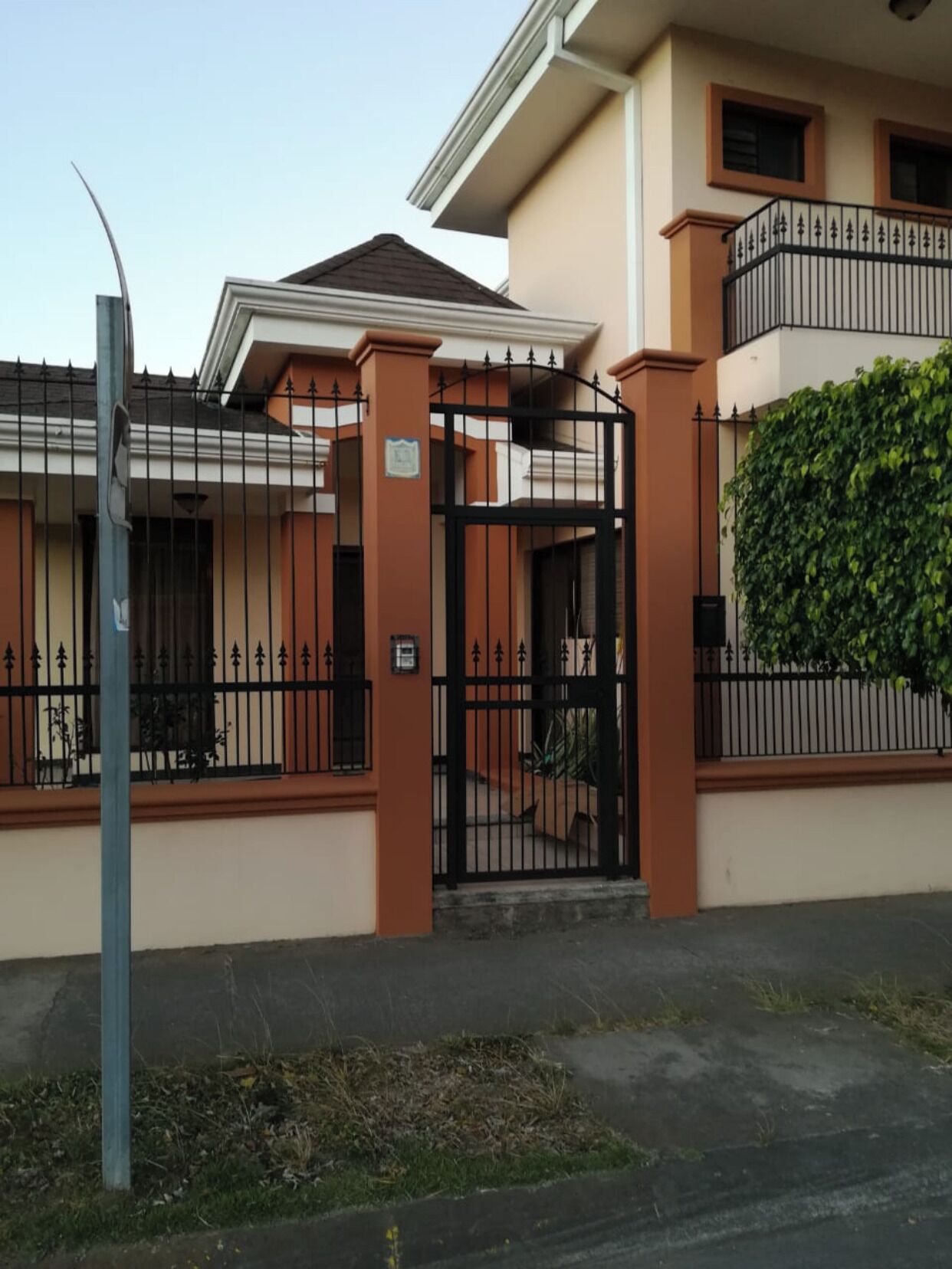 Edificio residencial con entrada porticada, balcón y muro verde.