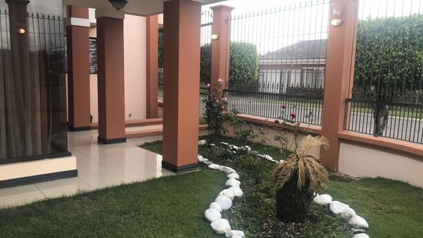 A covered outdoor area with a paved walkway, stone border, and a central plant. - Beautiful House, Master Bedroom With A Jacuzzi, Private Balcony, Mountain View! (El Tejar del Guarco)
