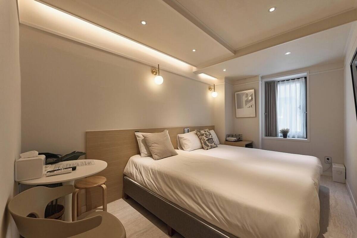 Un dormitorio moderno con cama, mesita de noche y escritorio con silla.