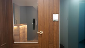 Una puerta de madera con un panel de vidrio, un escalón que lleva a un piso de baldosas y una lámpara en el techo.