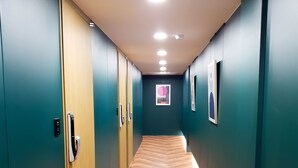 Un pasillo con paredes verde azulado, piso de madera y luces empotradas en el techo.