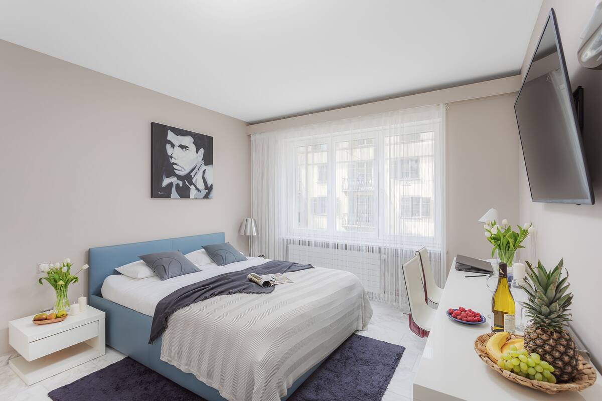 A modern bedroom with a bed, bedside table, and a TV mounted on the wall.