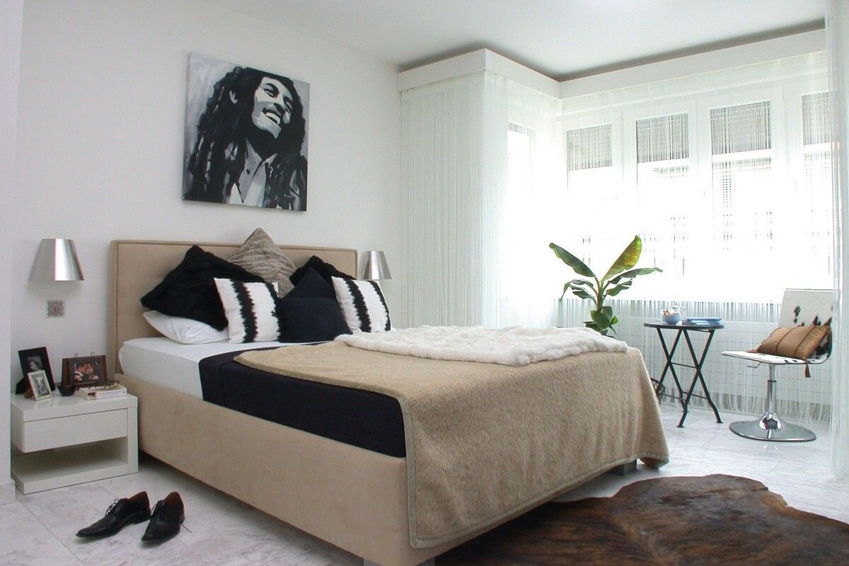 A bedroom with a bed, bedside tables, a chair, and a window with curtains.