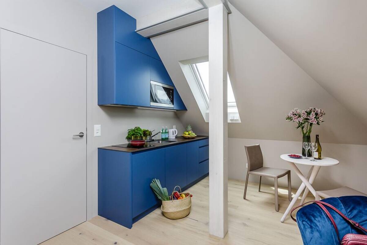A compact kitchen with blue cabinets, a microwave, and a small dining area with a table and chairs.