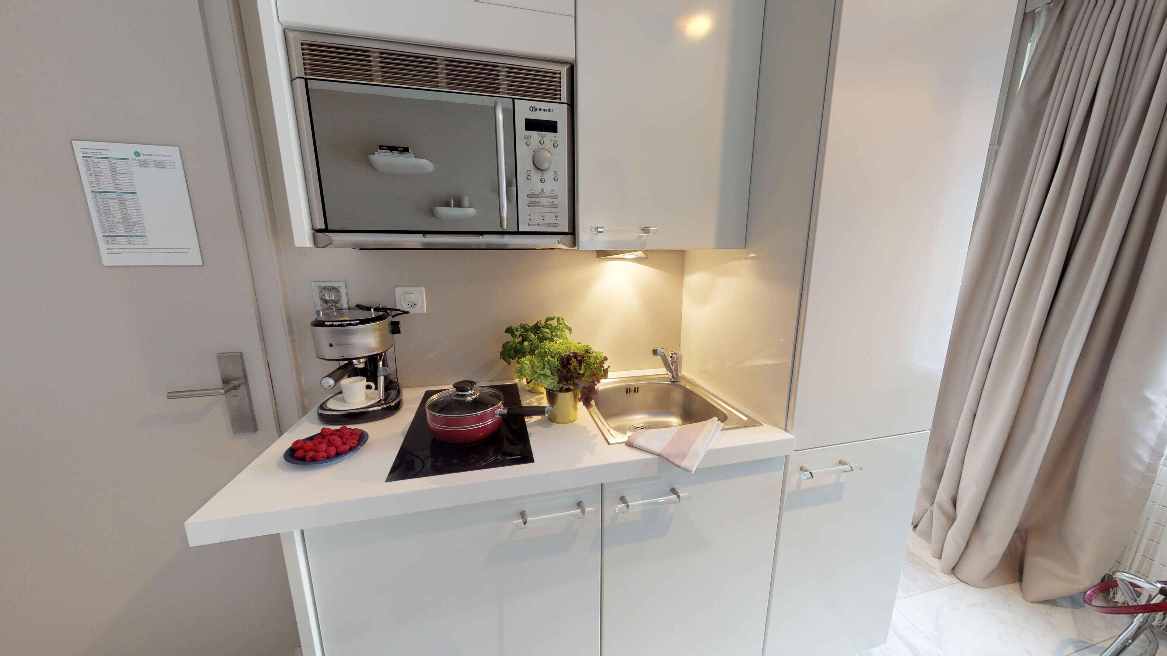 A modern kitchenette with a built-in microwave, coffee maker, and a sink.