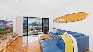 A modern living room with a blue sofa, wooden coffee table, and a surfboard mounted on the wall.