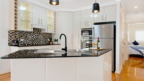 A modern kitchen with white cabinets, a black countertop, and stainless steel appliances.