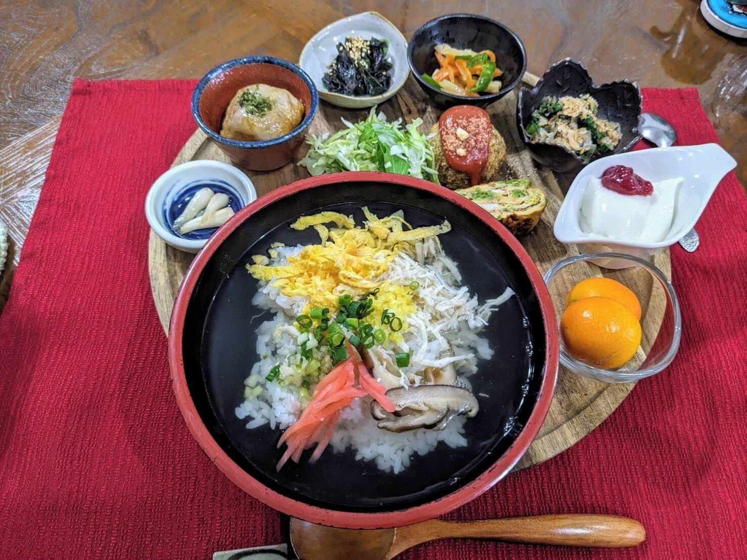 A meal with rice, vegetables, and various side dishes on a wooden table.