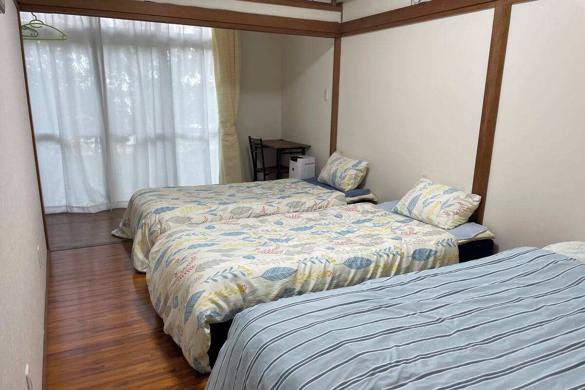 Ein Zimmer mit zwei Betten, Holzboden, einem Sessel und einem Tisch.