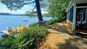 A lakeside cabin with a dock, outdoor seating, and a covered porch.