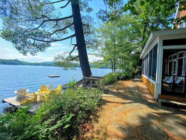 A lakeside cabin with a dock, outdoor seating, and a covered porch.
