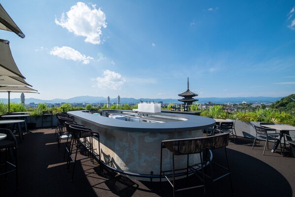 An outdoor bar area with a panoramic view of a pagoda and mountains.