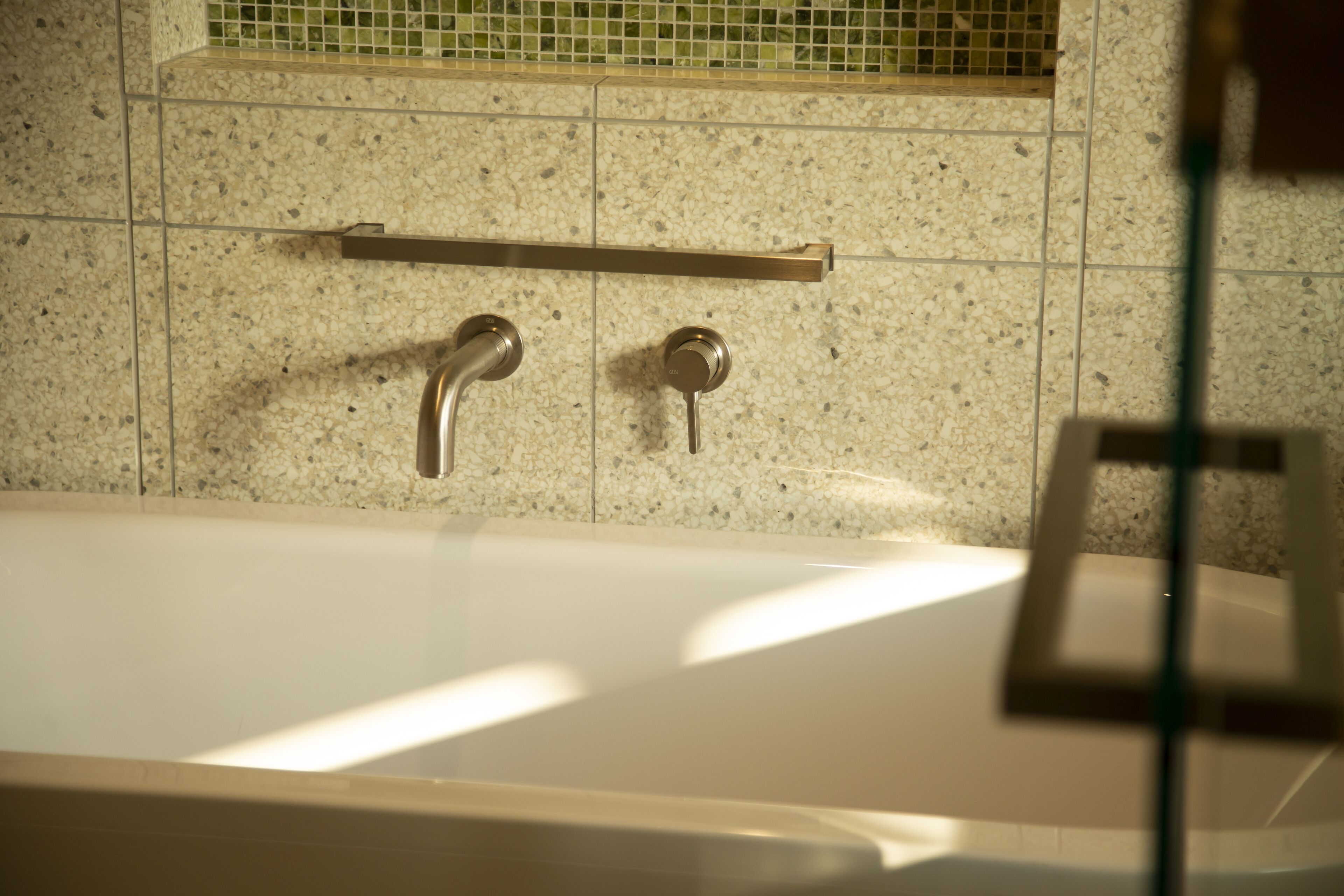 A bathroom with a bathtub, a towel rack, and a tiled wall.